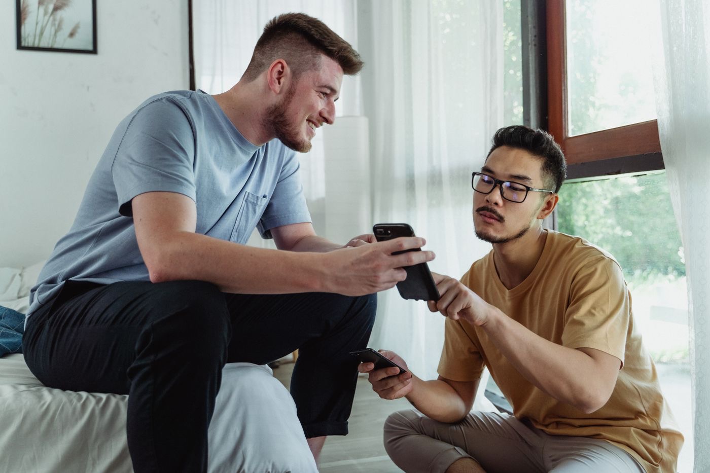 Two young men on a couch comparing their phones