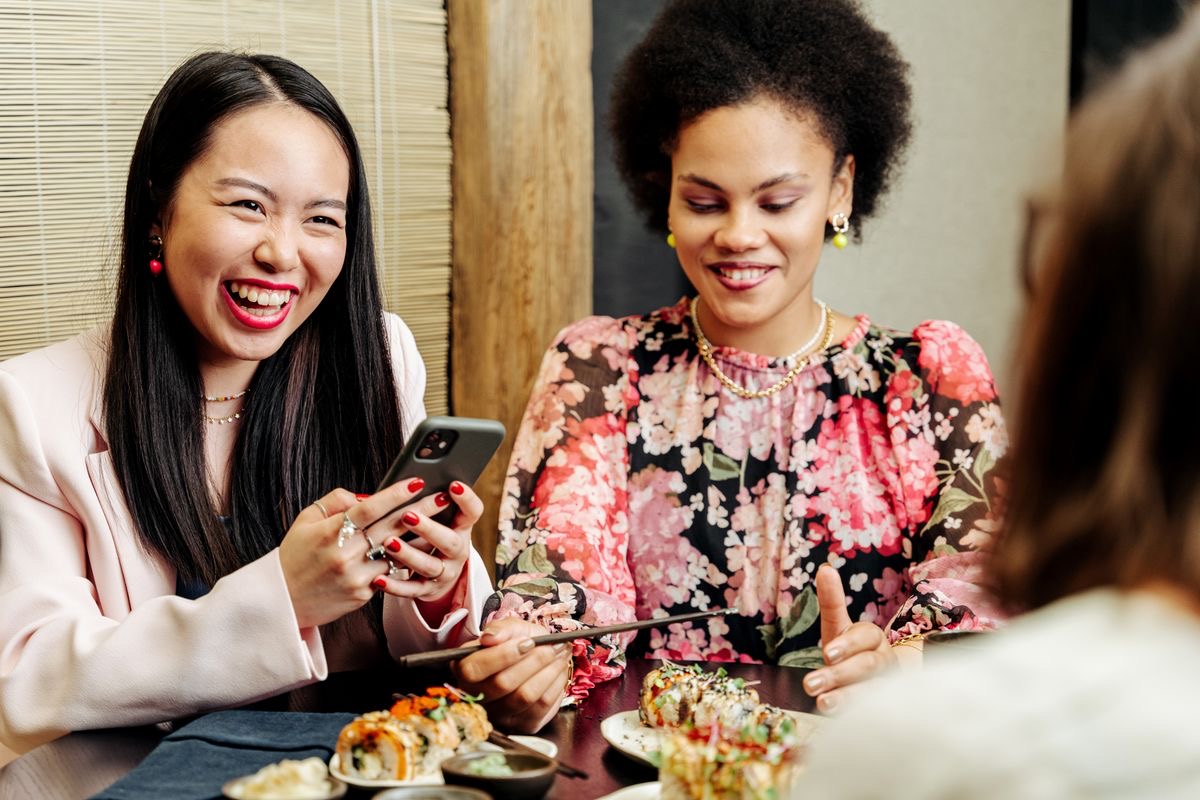 Two friends laughing over dinner at a restaurant
